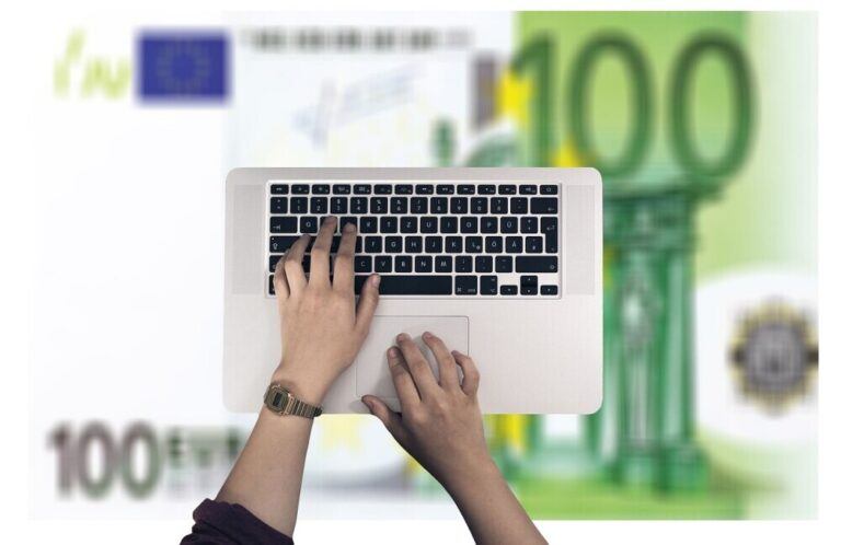 100 dollar bills sitting under a laptop