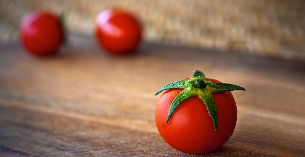 close up of a tomato with two tomatoes in the background